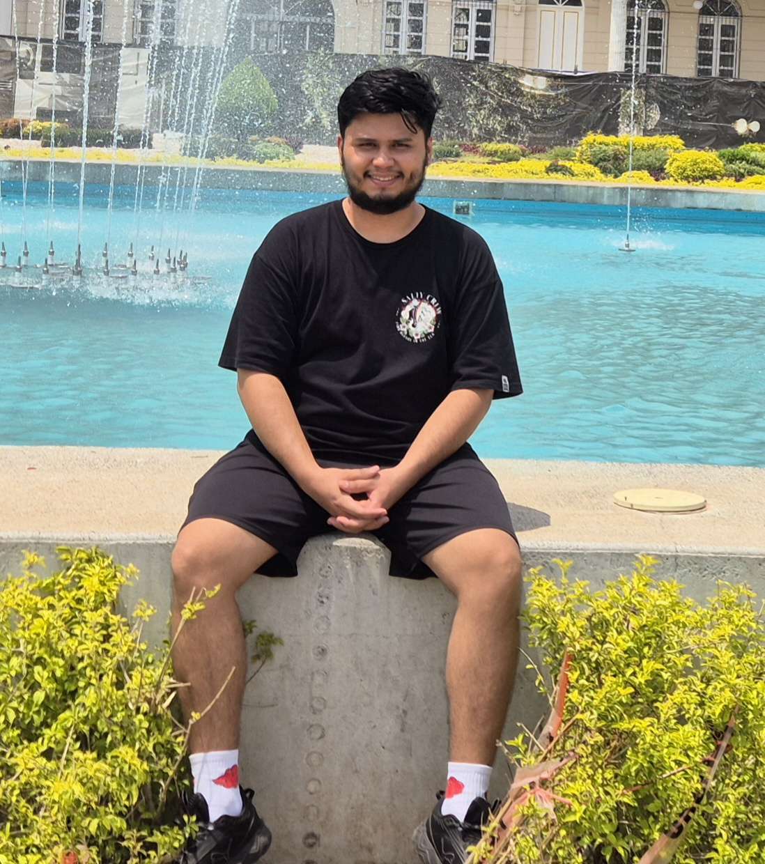 Bryan smiling, sitting on the edge of a fountain